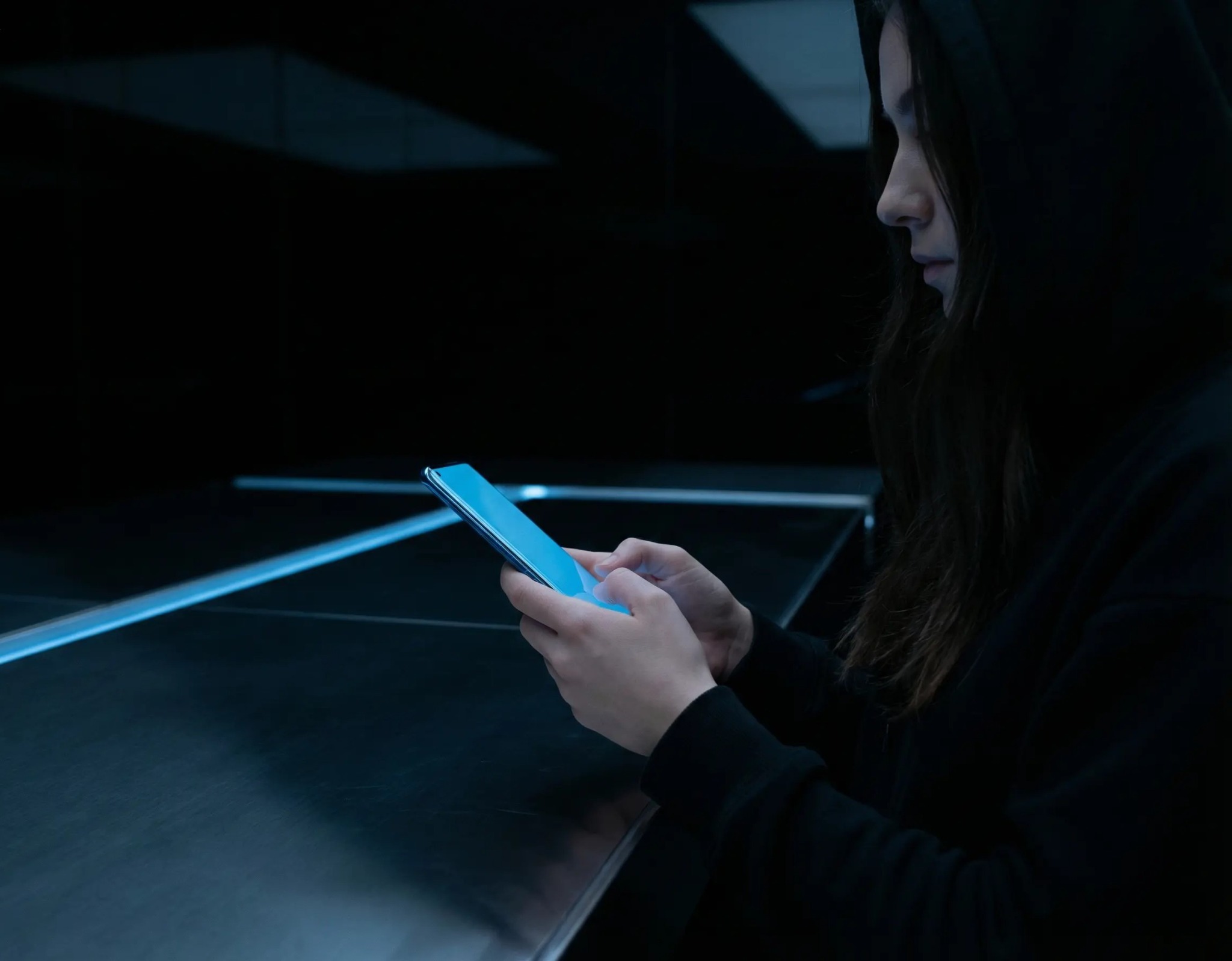 Créatrice sur téléphone dans un environnement sombre et moderne